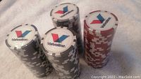 Four stacks of Valvoline branded poker chips in different colors: black, gray, red, and white on a light fabric background.