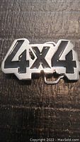 Front view of the metal 4x4 truck belt buckle showing the raised silver-tone lettering with black enamel fill.