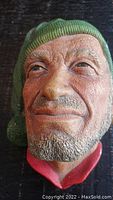 Front face close-up of vintage Bossons head figurine showing facial details and green knit cap.