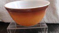 Photo showing side perspective of vintage Pyrex bowl, highlighting brown gradient exterior and white interior.