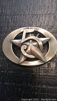 Front angled view of oval brass-tone belt buckle depicting the number '5' and star design.