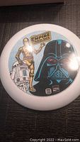 White plastic Frisbee with circular multi-character Star Wars The Empire Strikes Back graphic and sponsor logos