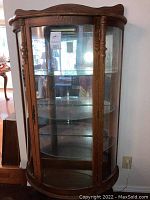 Full view of the curio cabinet showing medium oak finish with glass front and sides.