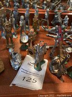Wide view of assorted painted metal and plastic toy soldiers in various poses on wooden surface