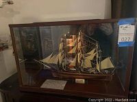 Front view of ship model in glass display case showing sails and rigging