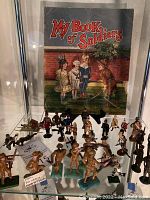 Frontal view of vintage book and assorted soldier figurines arranged in front