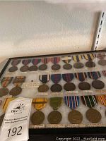 Display case showing two full rows of assorted campaign medals and ribbons
