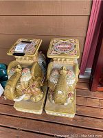 Pair of yellow ceramic elephant stools shown front view on wooden deck
