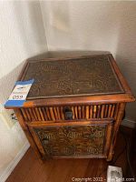 Front view of bamboo cabinet showing carved top panel, drawer and cabinet door
