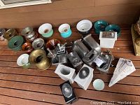 Overview photo of various vintage spittoons, ceramic pots, canisters, and bowls displayed on wooden floor