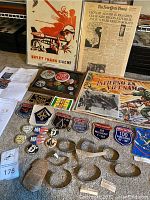 Overview of ephemera on carpet showing newspaper, posters, photos, patches, buttons, pins, and silver bracelets.