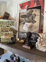 Overview of lot on wooden shelf showing poster, figurine, bust, tank