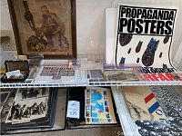 Overview of items on shelves including framed print, poster booklets, albums, postcards, jewelry cases