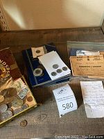 Photo of assorted ration books, coins, and paper currency spread out on a table including ration books in plastic sleeves, loose coins, and some notes handwritten on papers.