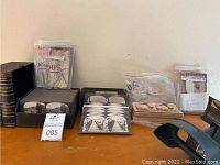 Overview of two bound volumes, a metal stereo viewer at right, a box of loose stereo cards and sealed bags of additional cards on a tabletop