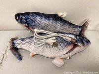 Two realistic fish-shaped electronic cat toys with USB charging cables placed on a flat surface.