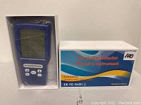 Photo of a blue handheld air quality detector device with a digital display and control buttons alongside its original box labeled 'Air quality detector Precision instrument'.