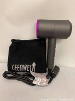 Side view showing the gray and purple hair dryer with attached power cord and black cloth pouch with 'Ceenwes' branding.