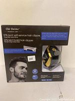 Front of the box showing product name, model, a photo of a man, and some features including large blade, fast haircut, and portability.