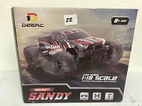 Photo showing front of original packaging box for Deerc brand 1:18 scale 4WD remote control car, model Sandy. Box indicates suitable for kids age 8+, features include 25 MPH speed, 4-wheel drive, and high-speed electric power.