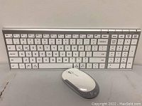Full view of white and gray wireless keyboard with full QWERTY layout including numeric keypad and wireless mouse in front.