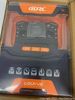 Photo of the drone's remote controller in packaging showing details of button features and branding.