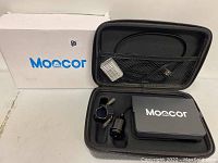 MOOCOR branded white box, black carrying case open showing diving camera, monitor and accessories inside foam cutouts