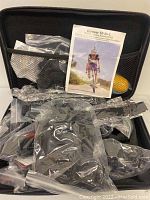 Photo of the Neewer 50-in-1 accessory kit mostly sealed in plastic inside a black carrying case with instruction manual visible