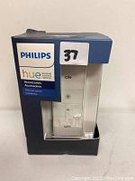Front view of original boxed Philips Hue dimmer switch showing product inside the box with Philips branding and control buttons visible.
