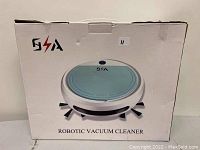 Box showing the front image of the robotic vacuum cleaner, white with blue top and black side brushes, with the text 'ROBOTIC VACUUM CLEANER' and logo.