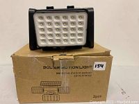 Photo of one solar motion sensor light sitting on top of its packaging box labeled 'Solar Motion Light, sensitive motion sensor, save energy, 2 pcs'.