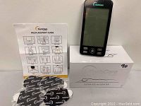 Photo of the TechCare massager device, pad placement guide, adhesive pads, and product box.