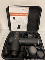 Wattne muscle stimulator massage gun inside carrying case with four different massage attachments and power cord, alongside user manual.