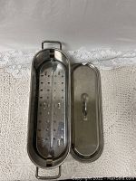 Aluminum salmon roaster with perforated inner tray removed and placed beside the lid.