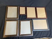 Seven assorted wood picture frames shown on black background. Various sizes and wood finishes visible.