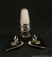 Photo of silver-tone vase with textured top and smooth bottom with wrap design, accompanied by two heart-shaped candle holders with bird figurines.