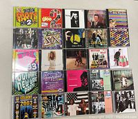 Multiple CD cases arranged flatly, showing a variety of album covers including party mixes, popular artists, and compilations.