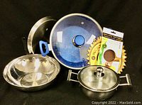 Flavourstone cookware pot with blue handles, tempered glass lid, nearby stainless steel wok and steel pot with lid, silicone microwave lid included