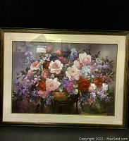 Framed print of garden flowers in a brass container showing front view, vibrant colors and signature visible.