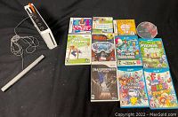 Photo showing Nintendo Wii console with sensor bar, remote, and 11 Nintendo games including Wii U titles.