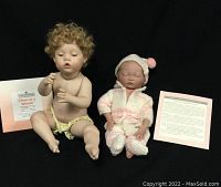 Both porcelain baby dolls seated, showing front view with accompanying certification and description cards