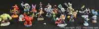 Photo showing over 25 Skylander figurines including Hulk and Ironman with some wear and damage on a black background