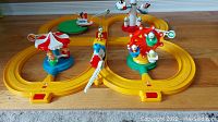 Overview of assembled playset showing yellow figure-eight track, carousel, boat, rocket tower, Ferris wheel with cartoon duck characters