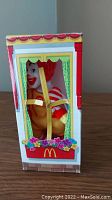 Front view of the Ronald McDonald figurine inside its original box, showing the house-style window with flower box and brick pattern base.