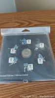 Sealed Limited Edition 2010 Lucky Loonie Team Canada hockey set with pins and coin on black backing inside plastic.