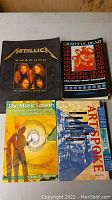 Photo showing four music-related books: Metallica biography, Grateful Dead book, Victor Wooten's The Music Lesson, and Artspoke book.