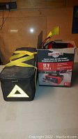 Photo showing the Motomaster battery charger box and the Justin Case emergency road kit in black soft carrying case with yellow straps