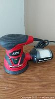 Right side angle view of the Skil orbital sander with micro-filtration dust collector on wooden surface.