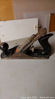 Side view of Stanley Handyman woodworking plane showing metal body, wooden handles, and blade mechanism