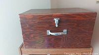 Front view of the wooden storage box showing the wood grain, latch, and handle.